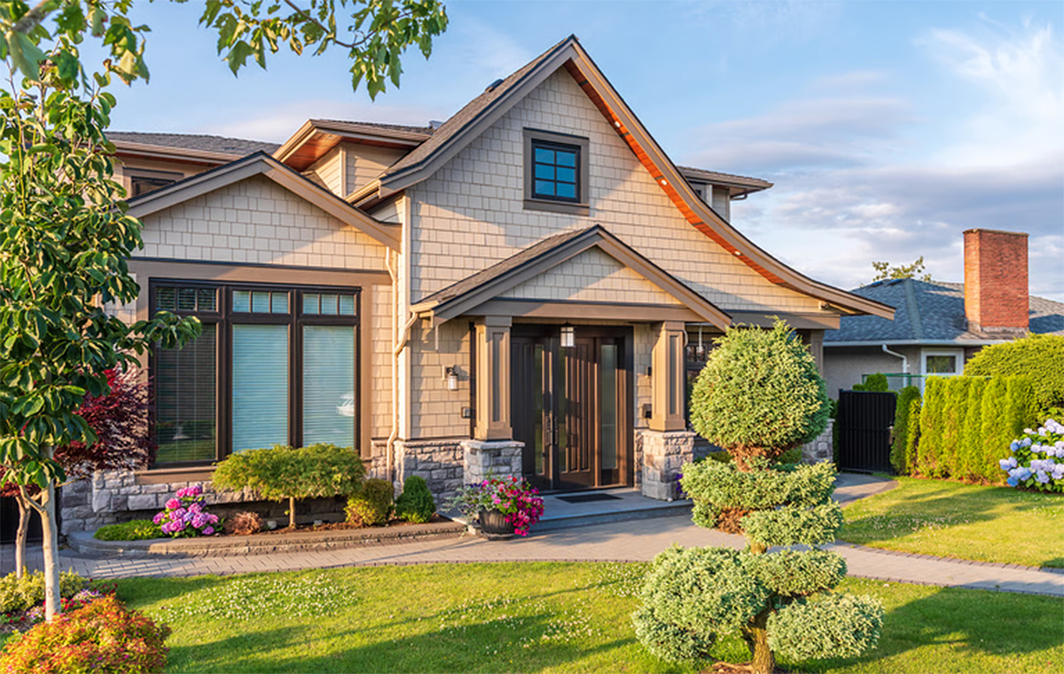 Modern suburban home with landscaped yard and stone pillars, representing the $400K home purchase discussed in the mortgage affordability guide.