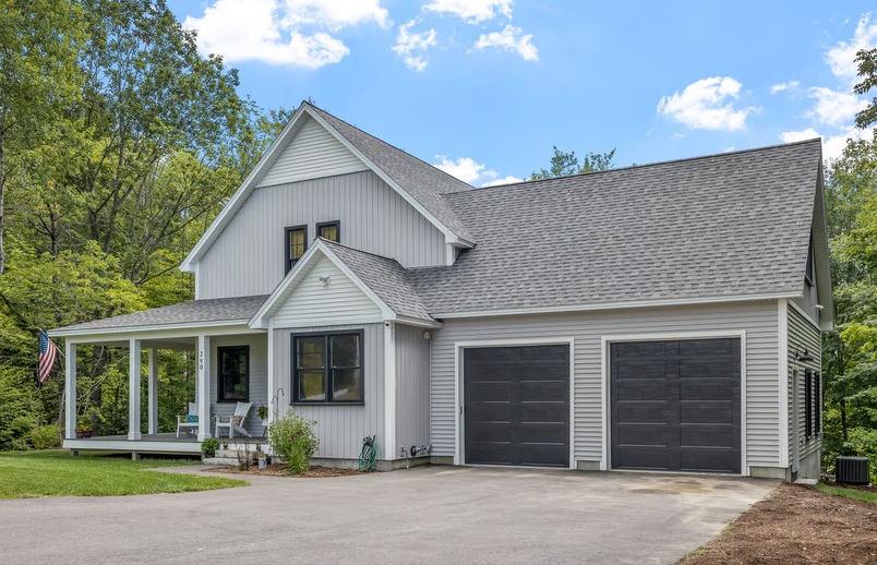 Light grey two-story modern farmhouse with a two-car garage, front porch, and black accents, illustrating out-of-state home buying options.